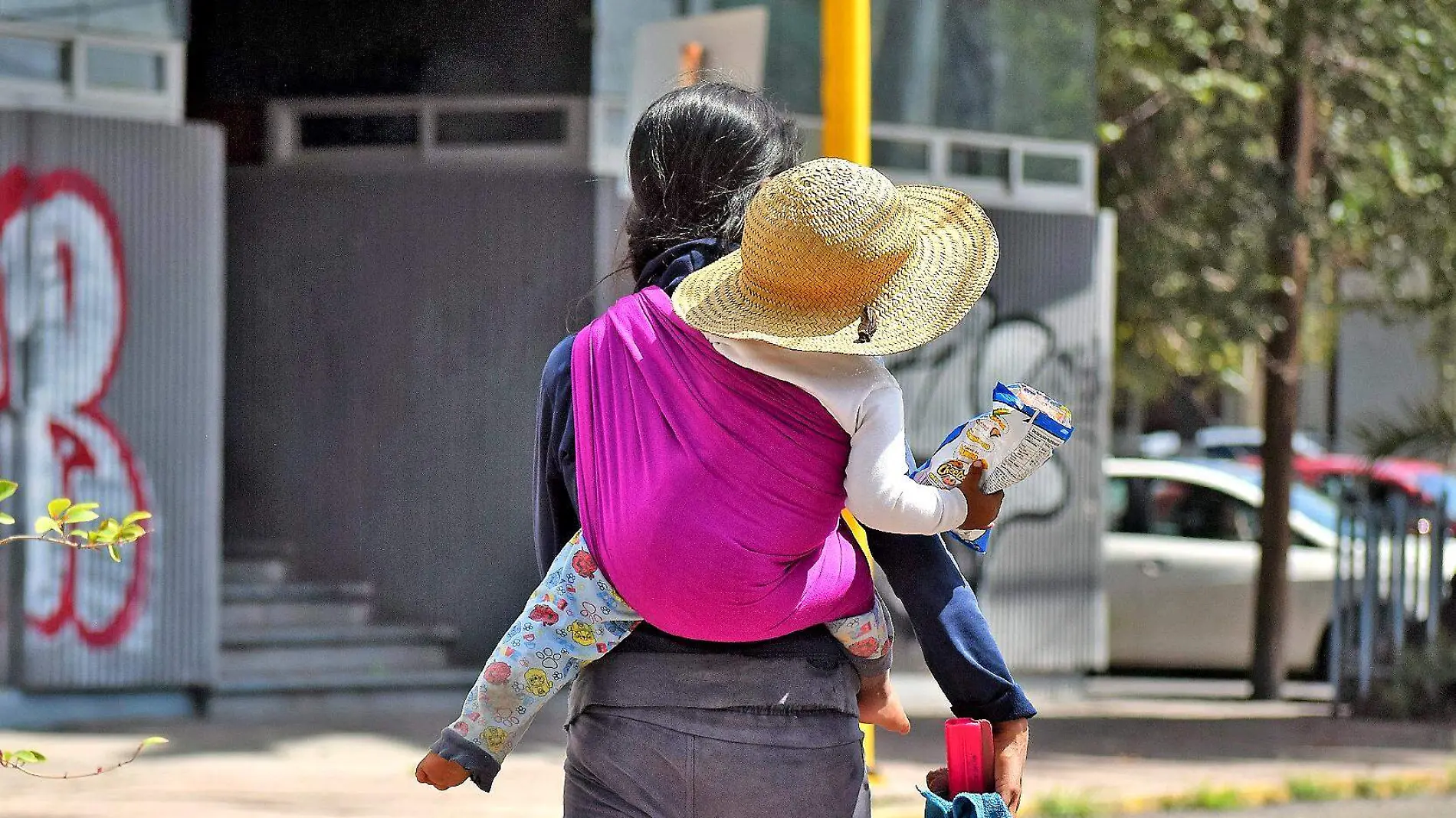 joven carga a un bebé en su espalda